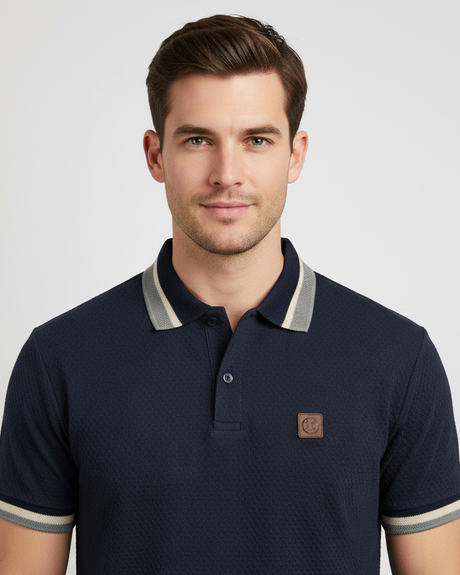 Man wearing navy polo shirt with grey tipped collar, upper body