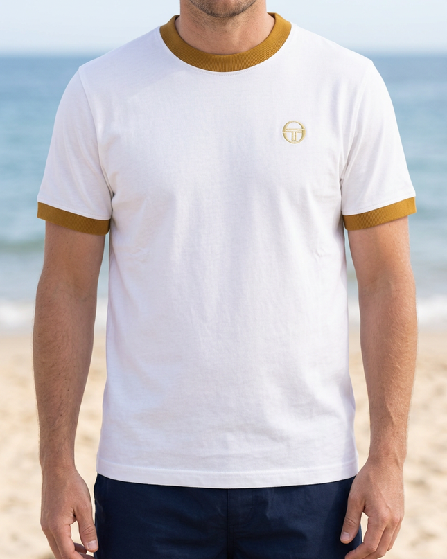 White male model wearing the white T-shirt with mustard trims on a summer beach